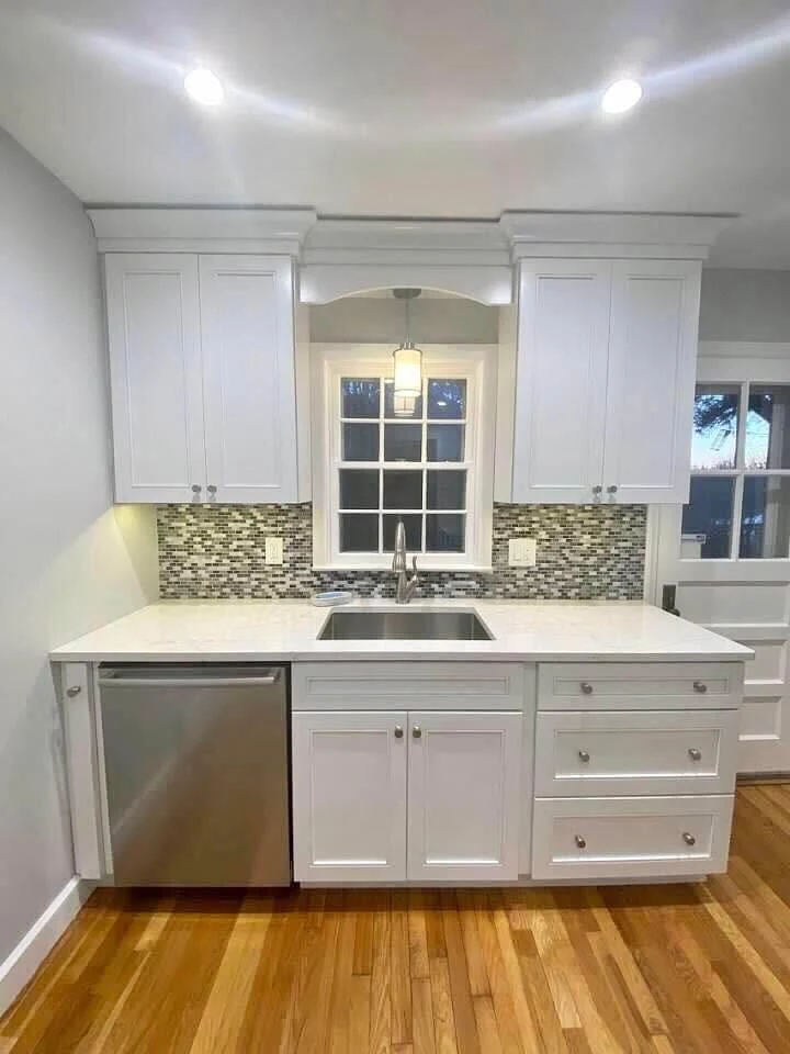 White custom cabinets surrounding a sink and window