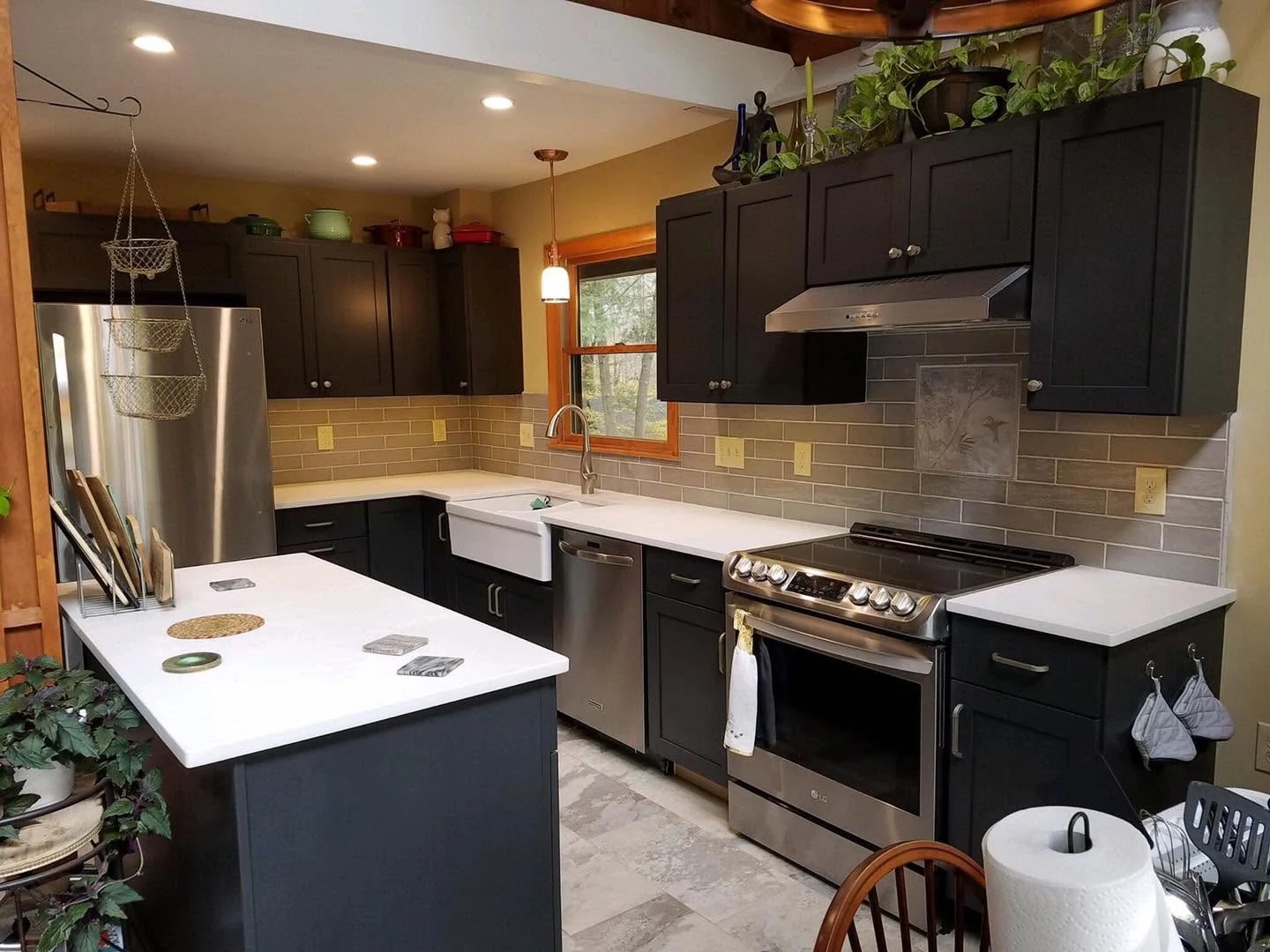 Remodeled kitchen with charcoal cabinets and white counters